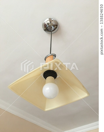 Light fixture hangs from ceiling in a room with plain walls and simple design 138824650