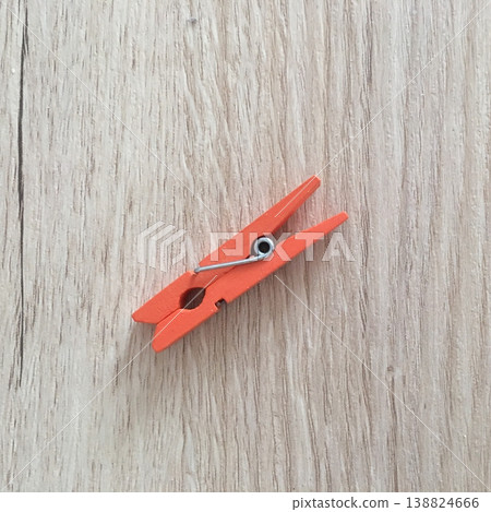 Bright orange clothespin rests on light wooden surface creating a simple and clear visual focus for everyday items in use Bright orange clothespin rests on light wooden surface creating a simple and clear visual focus for everyday items in use 138824666
