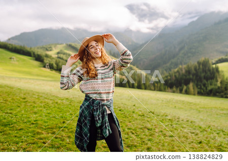 Cheerful happy woman smiles, laughs, emotional in nature, against backdrop of mountain landscapes. 138824829