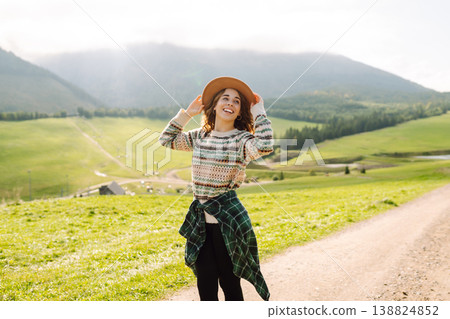 Young woman traveler explores new trails in green valley against backdrop of mountains. Wanderlust. Young woman traveler explores new trails in green valley against backdrop of mountains. Wanderlust. 138824852