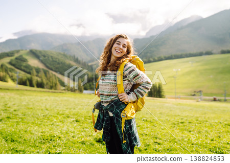 Female tourist with yellow backpack on top of mountain enjoying view of valley. Hiking concept. 138824853