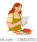 Woman in apron reads recipe and prepares vegetables. Home cooking scene featuring healthy food 138825352