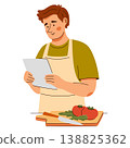 Smiling man in apron reads recipe and prepares vegetables. Home cooking scene featuring healthy food 138825362