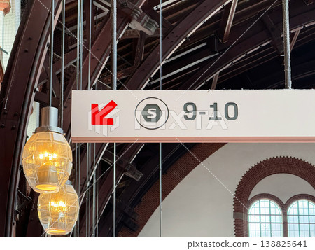 Railway station platform sign showing track numbers 9-10 with direction arrow in historic interior. 138825641