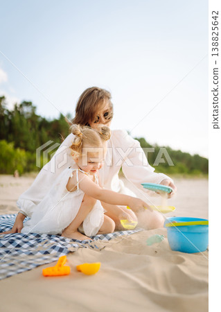 Mother and daughter enjoying time at the beach. Plays toys. Family vacation. Mother and daughter enjoying time at the beach. Plays toys. Family vacation. 138825642
