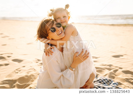 Portrait of mother and daughter enjoying a beach stroll at sunset. Moment of love and playfulness Portrait of mother and daughter enjoying a beach stroll at sunset. Moment of love and playfulness 138825643