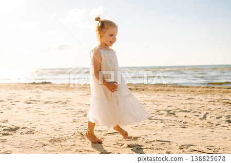 Young girl joyfully plays on the sandy beach during sunset, enjoying a carefree moment by the ocean Young girl joyfully plays on the sandy beach during sunset, enjoying a carefree moment by the ocean 138825678