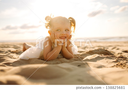 Young girl joyfully plays on the sandy beach during sunset, enjoying a carefree moment by the ocean 138825681