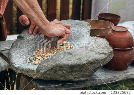 Human hand rotating an ancient stone grinding machine for smashing grains. Handmade manual equipment grind mill 138825682