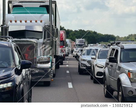Large freight truck and multiple passenger vehicles are stopped in dense traffic on a multi-lane highway. The scene represents transportation congestion, logistics delay, and real commuting conditions Large freight truck and multiple passenger vehicles are stopped in dense traffic on a multi-lane highway. The scene represents transportation congestion, logistics delay, and real commuting conditions 138825912