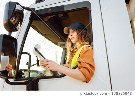 Portrait of beautiful young woman professional truck driver checking shipment list on a -parking lot 138825948
