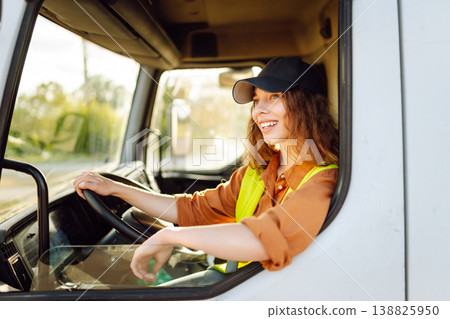 Portrait of beautiful young woman professional truck driver driving a big truck. Inside of vehicle 138825950