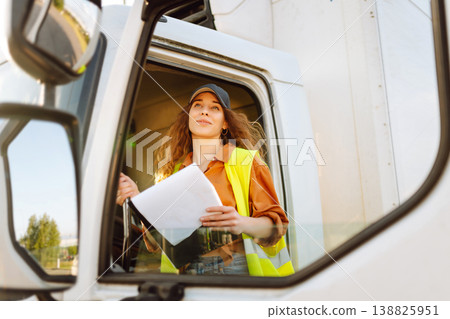 Portrait of beautiful young woman professional truck driver checking shipment list on a -parking lot 138825951