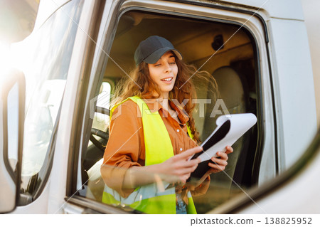 Portrait of beautiful young woman professional truck driver checking shipment list on a -parking lot 138825952