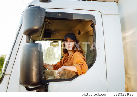 Portrait of beautiful young woman professional truck driver driving a big truck. Inside of vehicle 138825953
