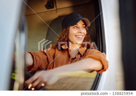 Portrait of beautiful young woman professional truck driver driving a big truck. Inside of vehicle 138825954