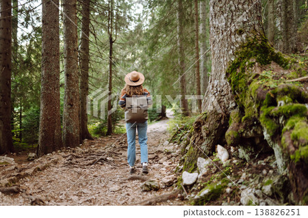 Woman with backpack hiking outdoors in the Forest. Trekking in the Pine Woods. Hiking lifestyle Woman with backpack hiking outdoors in the Forest. Trekking in the Pine Woods. Hiking lifestyle 138826251