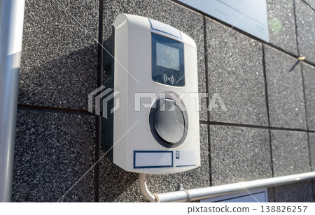 Electric vehicle charging socket on wall with contactless payment terminal modern EV charging station concept 138826257