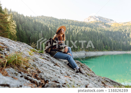 Young woman traveler enjoys fresh air and a beautiful view of the lake and mountains. Active life 138826289