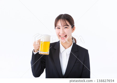 一位身穿西裝的年輕女子舉杯啤酒。 一位身穿西裝的年輕女子舉杯啤酒。 138827654