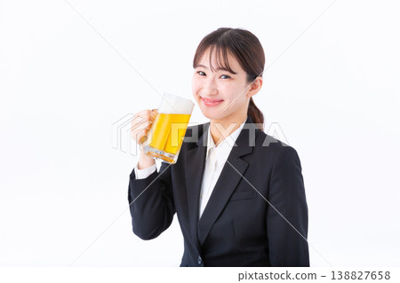 A young woman in a suit smiling and drinking beer. 138827658