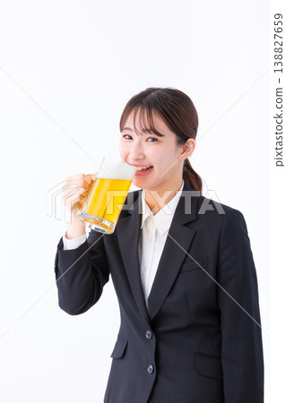 A young woman in a suit smiling and drinking beer. 138827659