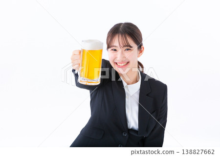 一位身穿西裝的年輕女子舉杯啤酒。 一位身穿西裝的年輕女子舉杯啤酒。 138827662