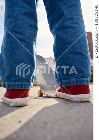Rear view of skateboard and red sneakers on suburban street Rear view of skateboard and red sneakers on suburban street 138828140