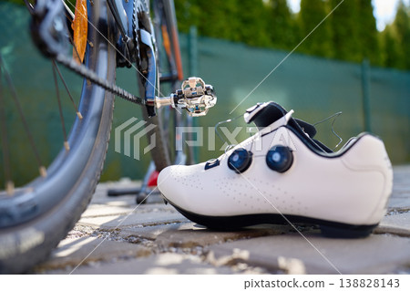 White cycling shoe beside a clipless pedal on a road bike 138828143