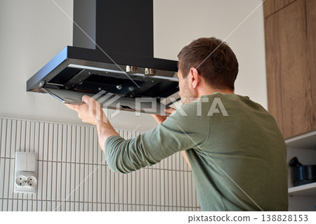 Man removing a filter from a modern kitchen hood Man removing a filter from a modern kitchen hood 138828153