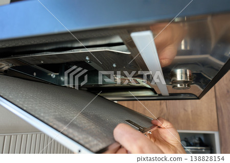 Removing filter from kitchen range hood for cleaning Removing filter from kitchen range hood for cleaning 138828154