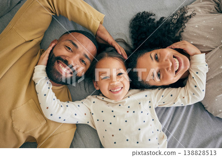 Happy family, top view and child relax or happy with parents together in the morning laughing in a bedroom on a bed. Smile, mom and dad enjoy quality time with kid with happiness, bonding and love Happy family, top view and child relax or happy with parents together in the morning laughing in a bedroom on a bed. Smile, mom and dad enjoy quality time with kid with happiness, bonding and love 138828513