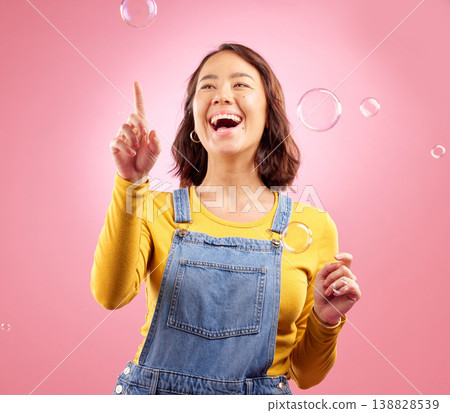 Happy, woman and laughing with bubbles in studio, pink background and excited to celebrate freedom, play and creativity. Asian female model pop soap bubble for funny, entertainment and burst of magic 138828539