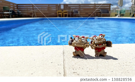 A Shisa statue relaxing by the poolside, against a blue sky and a resort summer scene. Awamori (Okinawan liquor). Okinawa Prefecture. A Shisa statue relaxing by the poolside, against a blue sky and a resort summer scene. Awamori (Okinawan liquor). Okinawa Prefecture. 138828556