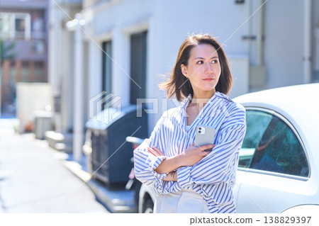 一位日本女性在戶外一邊用智慧型手機通話一邊凝視遠方的肖像。 一位日本女性在戶外一邊用智慧型手機通話一邊凝視遠方的肖像。 138829397