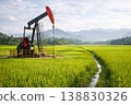 Oil drilling pumpjack in lush rice field landscape with mountains and blue sky 138830326