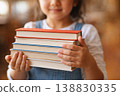 Child holding stack of books representing education learning and knowledge 138830335