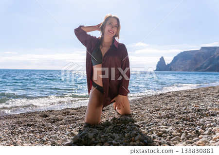 Beach woman vacation smiling on a pebble shore with ocean waves and rocky cliffs in the background 138830881