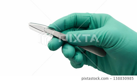 Gloved hand holding a sterile surgical scalpel with a plastic transparent safety shield or blade guard, representing sharps safety and operative precision 138830985
