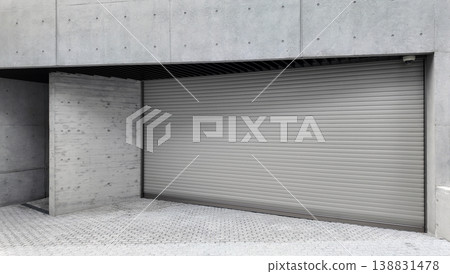 A large white metal car garage door on a concrete house. The modern luxury automotive building has a grey concrete driveway entrance. 138831478