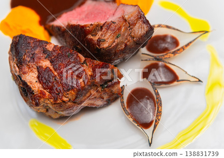 Grilled beef steak served with sauce and colorful garnishes on a plate Grilled beef steak served with sauce and colorful garnishes on a plate 138831739
