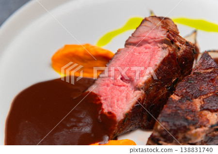 Sliced beef steak with sauce and colorful puree on a white plate 138831740