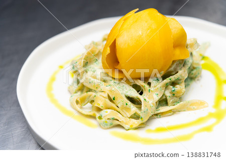 Fresh pasta dish topped with mango and green herb sauce on white plate 138831748
