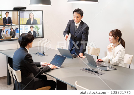 A scene of exchanging opinions in a business meeting that combines in-person and online activities. 138831775