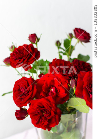 A vibrant bouquet of red roses fills a clear vase, showcasing the flowers' rich colors and lush green leaves, perfect for any occasion or home decor setting 138832805