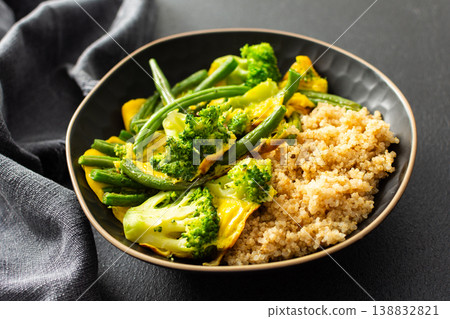 Quinoa bowl features boiled eggs, green beans, and broccoli. A fresh salad sits nearby. A cup of coffee completes the healthy breakfast setting 138832821