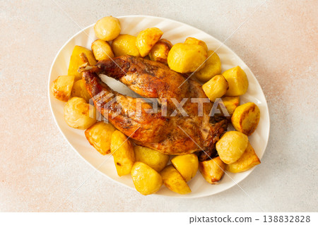 A beautifully presented dish features a whole baked rabbit surrounded by tender, golden-roasted potatoes. This comforting meal is perfect for family gatherings or special occasions. A beautifully presented dish features a whole baked rabbit surrounded by tender, golden-roasted potatoes. This comforting meal is perfect for family gatherings or special occasions. 138832828