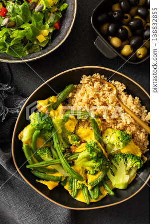 Healthy breakfast consists of a quinoa bowl with boiled eggs, green beans, and broccoli placed on a dark surface next to a cup of coffee and a woven cloth Healthy breakfast consists of a quinoa bowl with boiled eggs, green beans, and broccoli placed on a dark surface next to a cup of coffee and a woven cloth 138832855