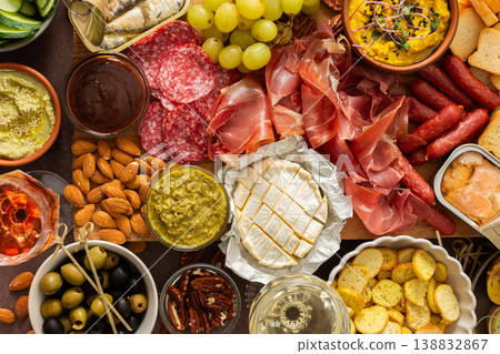 Taste a variety of flavors with this charcuterie board filled with cheese, sausages, hummus, nuts, and fresh sandwiches, perfect for any gathering 138832867