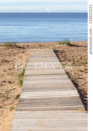 A wooden boardwalk leads across coastal sandy dunes A wooden boardwalk leads across coastal sandy dunes 138833221